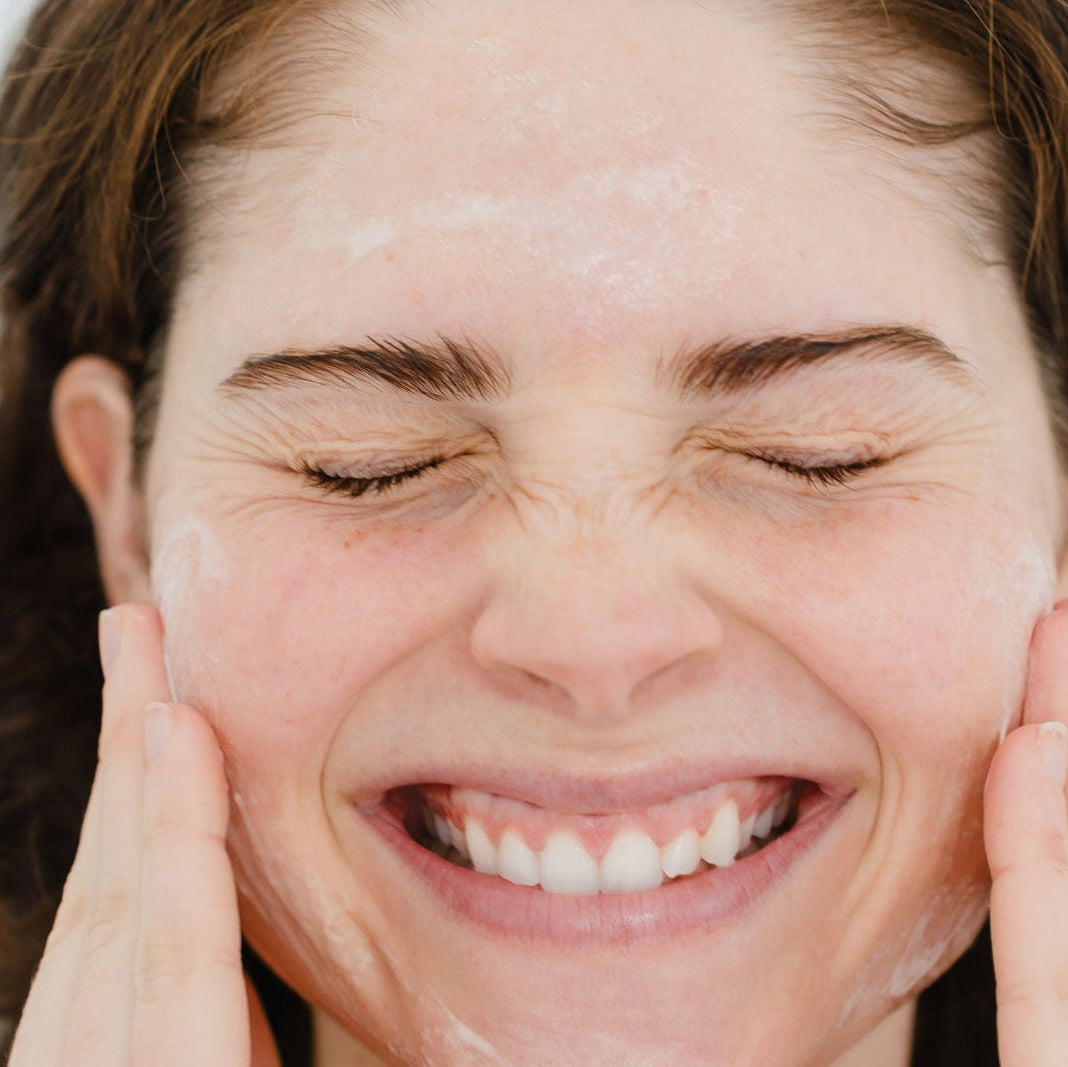 Woman applying cream to her face with a white background